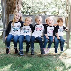 four children sitting on a bench wearing matching shirts