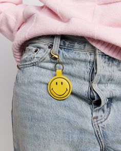 a yellow smiley face keychain hanging from the back of someone's jeans