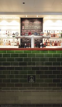 the bar is stocked with liquor bottles and other items on display in front of a chalkboard