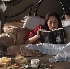 a woman laying in bed reading a book