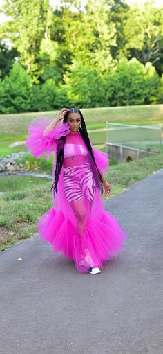 a woman in a pink dress is walking down the street with her hands on her head