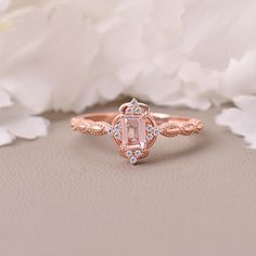 an engagement ring with a pink morganite surrounded by white flowers on a beige background