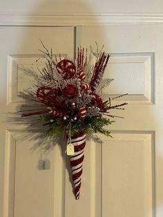 a red and white christmas decoration hanging on the front door with candy canes in it