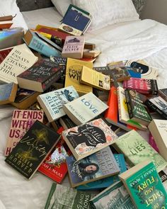 a pile of books sitting on top of a bed next to a white comforter