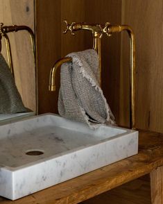 a white sink sitting on top of a wooden counter next to a mirror and towel rack