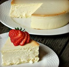 two plates with cheesecake and a strawberry on top