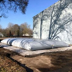 three large water tanks sitting in front of a white building with shadows on the wall