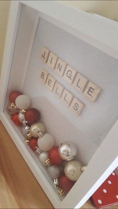 a display case filled with christmas ornaments on top of a wooden floor next to a red and white polka dot pillow