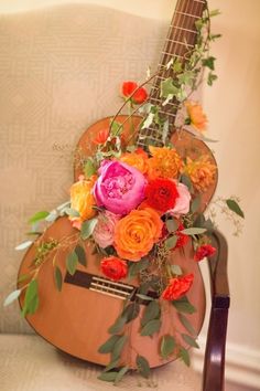 an acoustic guitar decorated with flowers and greenery is on the instagram page for wedding photos