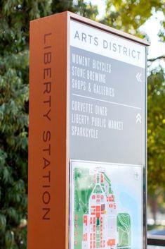 a sign for liberty station in front of some trees and cars parked on the street