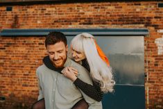 a man holding a woman in front of a brick building