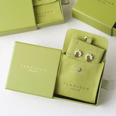 three pairs of earrings in a green box