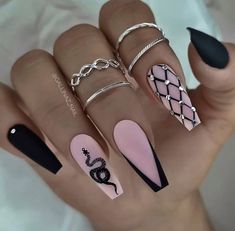 a woman's hand with black and pink nail polishes on it, including rings