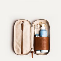 an open travel bag with personal items in it on a white surface, including toothbrushes and lotion bottles