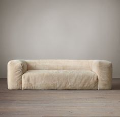 a white couch sitting on top of a wooden floor next to a gray wall in an empty room