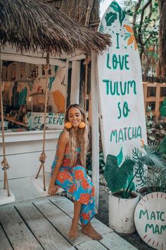 a woman sitting in front of a sign that says i love tujum so matcha