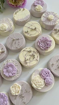 many different types of decorated cakes on a table with flowers in the middle and one is purple