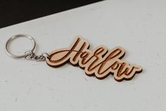 a wooden keychain with the word hello written in cursive writing on it