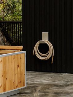 a wooden box with a hose attached to it next to a black fence and trees