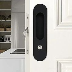 an open door with a black handle in front of a white kitchen counter and cabinets