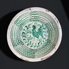 a green and white bowl sitting on top of a black table next to a wall