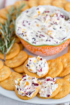 crackers with cranberry cheese and rosemary garnish are on a platter