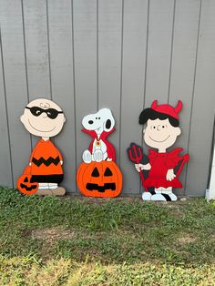 three wooden cutouts of charlie brown, snoopman and jack - o - lantern