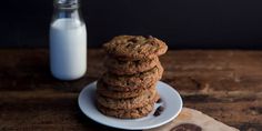 a stack of cookies sitting on top of a white plate next to a bottle of milk