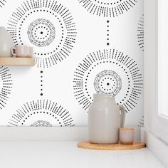 a white vase sitting on top of a counter next to a wallpapered wall