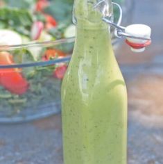 a glass bottle filled with dressing next to a salad