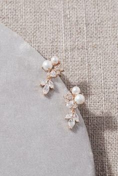 a pair of pearl and crystal earrings on top of a gray stone plated surface