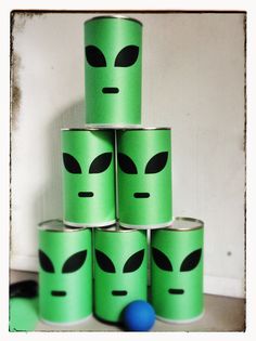 a stack of green cans with faces painted on them