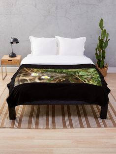 a close up of a bed with a plant in the background on a wooden floor