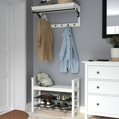 a coat rack with shoes and coats hanging on the wall next to a white dresser