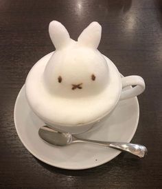 a white plate topped with a cup and saucer filled with whipped cream in the shape of a bunny