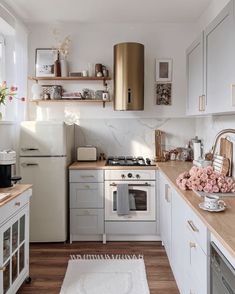 a kitchen with white cabinets and wooden counter tops, gold accents on the hood over the stove