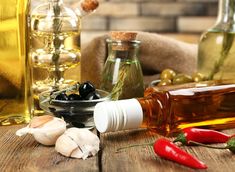 an assortment of olives, garlic and oil on a wooden table with other bottles