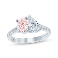 an engagement ring with two pear shaped pink and white diamonds on the sides, set in 18k white gold