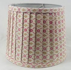 a lamp shade with pink and gold designs on it's sides, sitting on a white surface