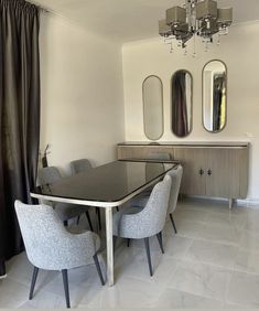 a dining room table with four chairs and a chandelier hanging from the ceiling