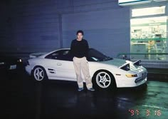 a man standing next to a white sports car