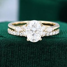 a diamond engagement ring on top of a green velvet cushioned surface with the center stone surrounded by three smaller round diamonds