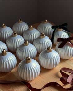 twelve white pumpkins with bows on a wooden table