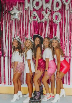 a group of young women standing next to each other in front of a pink curtain