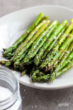 asparagus on a white plate next to salt and pepper