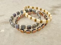 three bracelets made out of wood and stone beads on a marble counter top, with one bead in the middle