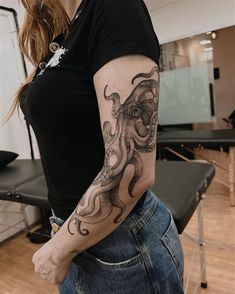 a woman with a tattoo on her arm and an octopus in the middle of her arm