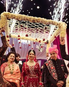 the bride and groom are walking down the aisle with fireworks in the sky behind them