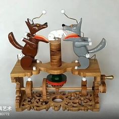 three wooden toy animals on top of a table with spools of thread in front of them