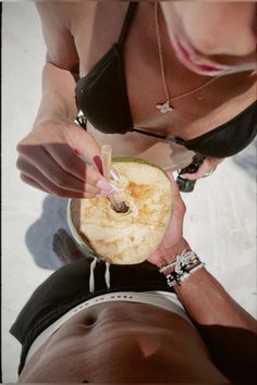 a woman holding an apple in her right hand while laying on the ground with another person